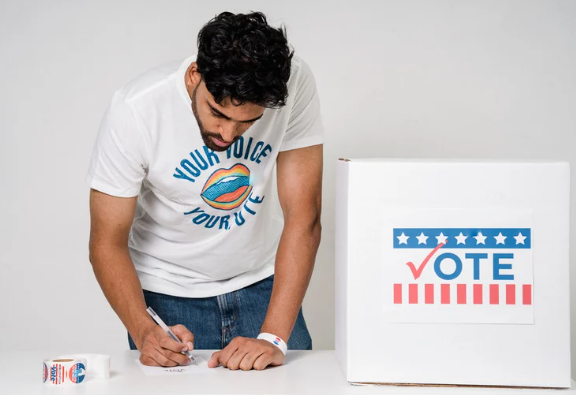 A voter completing a ballot beside a ballot box.